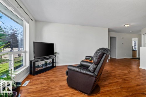 Expansive picture window, rich wood-finish flooring, recessed lighting, and a neutral wall palette - #92 13320 124 St Nw, Edmonton, AB 