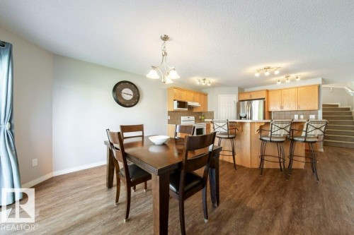 Wood-finish flooring throughout, with a dining area featuring a metal chandelier - 16120 138 Street Nw, Edmonton, AB 