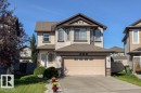 Two-story residence featuring light-colored siding, a brown roof, and an integrated garage with a light-toned door - 16120 138 Street Nw, Edmonton, AB 