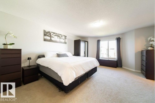 Expansive carpeted room featuring a large window, light-toned walls, and a ceiling-mounted light fixture - 16120 138 Street Nw, Edmonton, AB 