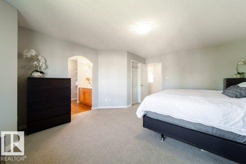 Neutral-toned carpeting, light gray wall paint, an arched doorway, and a ceiling-mounted light fixture - 16120 138 Street Nw, Edmonton, AB 