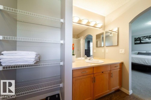 large vanity with integrated sinks, light wood-finish cabinetry, and overhead lighting - 16120 138 Street Nw, Edmonton, AB 