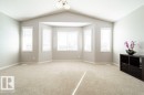 Spacious room featuring vaulted ceilings, recessed bay windows, neutral carpet flooring, and a semi-flush mount light fixture - 16120 138 Street Nw, Edmonton, AB 
