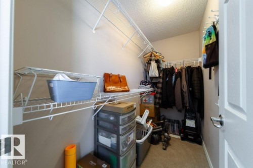 Walk-in closet featuring wire shelving, hanging rods, and neutral carpeting - 16120 138 Street Nw, Edmonton, AB 