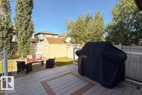 Wood-look composite decking with contrasting border, white railing, paved patio area, detached storage shed, and fenced perimeter - 16120 138 Street Nw, Edmonton, AB 