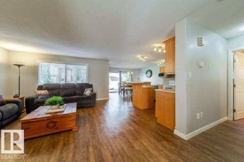 Wood-finish flooring throughout, light neutral wall paint, and a sliding glass door - 16120 138 Street Nw, Edmonton, AB 