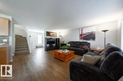 Wood-finish flooring, staircase with carpeted treads and white risers, light-toned cabinetry, light-toned countertops, and a white interior wall finish - 16120 138 Street Nw, Edmonton, AB 