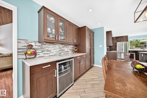 Warm wood-tone cabinetry with glass-front uppers, white countertop, and tiled backsplash - 8224 186 Street Nw, Edmonton, AB 