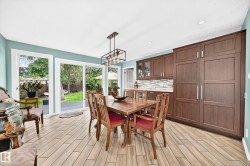 Wood-finish flooring, full-height cabinetry with integrated appliances, light blue painted walls, recessed lighting, and a modern chandelier - 