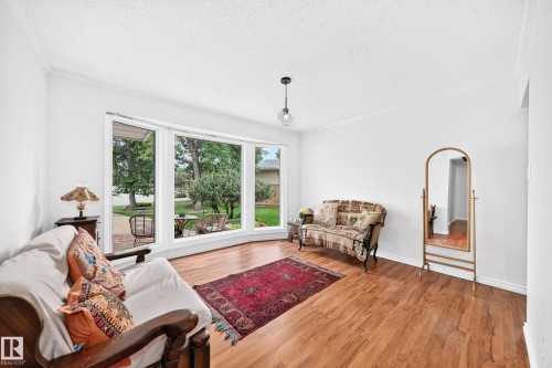 Large bay window, wood-finish flooring, white walls, crown molding, and a built-in ceiling light - 8224 186 Street Nw, Edmonton, AB 