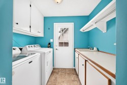 Dedicated laundry area featuring a utility sink, upper cabinetry, lower cabinetry, and a drying rack - 