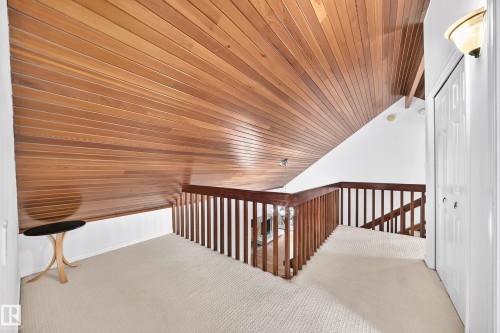 Vaulted wood-paneled ceiling, wood-finish railing, wall-mounted light fixture, and textured carpeting - 8224 186 Street Nw, Edmonton, AB 