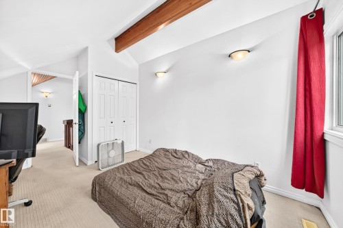 Vaulted ceiling with exposed wood beam, wall sconces, carpeted flooring, and bi-fold closet doors - 8224 186 Street Nw, Edmonton, AB 