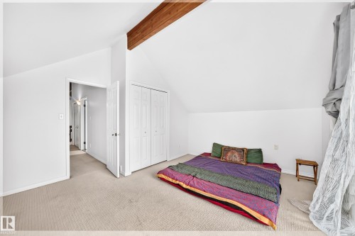 Spacious bedroom featuring vaulted ceilings with exposed wood beam, neutral carpeting, and abundant natural light - 8224 186 Street Nw, Edmonton, AB 