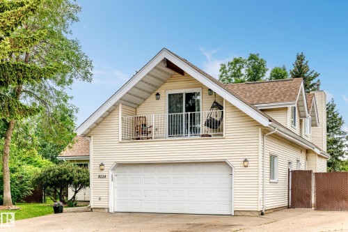 Two-car garage, upper balcony with sliding glass door, dormer windows, and light-colored siding - 8224 186 Street Nw, Edmonton, AB 