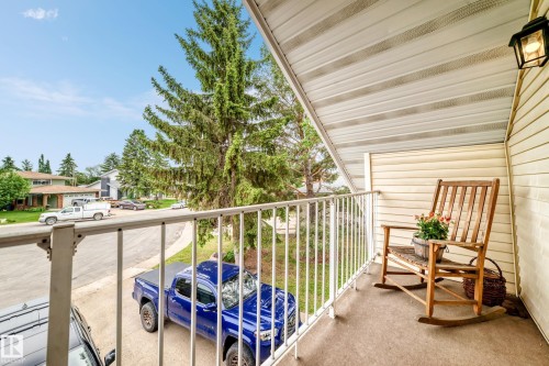 Balcony featuring slatted siding, a white metal railing, and an exterior wall light - 8224 186 Street Nw, Edmonton, AB 
