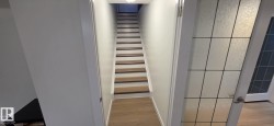 Recessed lighting illuminates the staircase with wood-finish treads and white risers - 