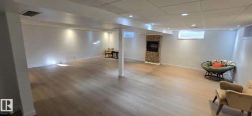 Spacious lower level featuring wood-finish flooring, recessed lighting, and a stacked stone fireplace - 8224 186 Street Nw, Edmonton, AB 