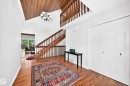 Foyer featuring wood-finish flooring, a wood-paneled vaulted ceiling, a chandelier, and a wood staircase with banister - 8224 186 Street Nw, Edmonton, AB 