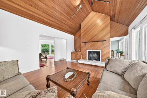 Vaulted wood-paneled ceiling, wood-finish flooring, wood-paneled fireplace, built-in cabinetry, and French doors - 8224 186 Street Nw, Edmonton, AB 