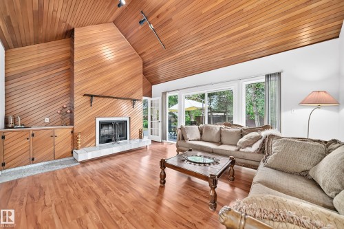 Vaulted wood-paneled ceiling, wood-finish flooring, built-in wet bar, wood-burning fireplace with a tile hearth, and French doors - 8224 186 Street Nw, Edmonton, AB 