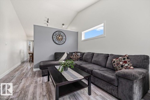 Vaulted ceiling, wood-finish flooring, accent wall, track lighting, and a horizontal window - 40 Hampton Place, Stony Plain, AB 