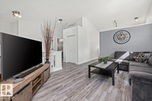 Vaulted ceilings with track lighting, wood-finish flooring, and a half-wall balustrade with white spindles - 40 Hampton Place, Stony Plain, AB 
