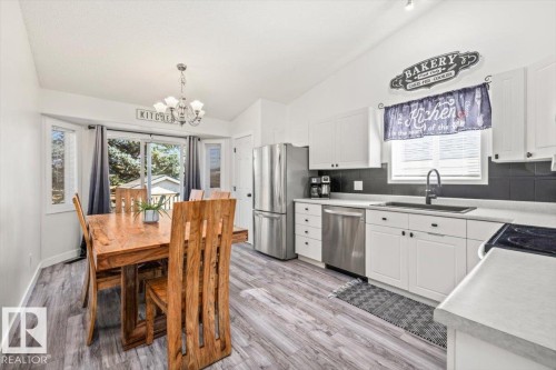 Vaulted ceiling, bay window, sliding glass door, white cabinetry, and wood-finish flooring - 40 Hampton Place, Stony Plain, AB 