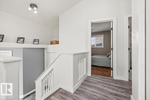 Upper-level landing with wood-finish flooring, white painted walls, and track lighting - 40 Hampton Place, Stony Plain, AB 