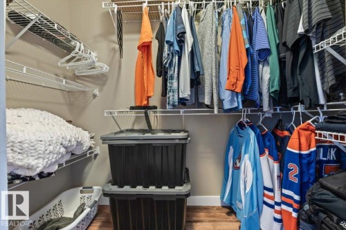 Customizable closet system with multiple white wire shelves and hanging rods, complemented by wood-finish flooring - 40 Hampton Place, Stony Plain, AB 