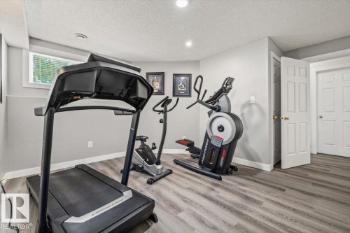 Recessed lighting with a textured ceiling, a window with horizontal blinds, and wood-finish flooring - 40 Hampton Place, Stony Plain, AB 