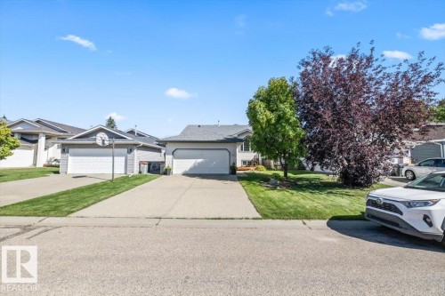 Two single-car garages, asphalt shingle roofing, and concrete driveways with grass strips - 40 Hampton Place, Stony Plain, AB 