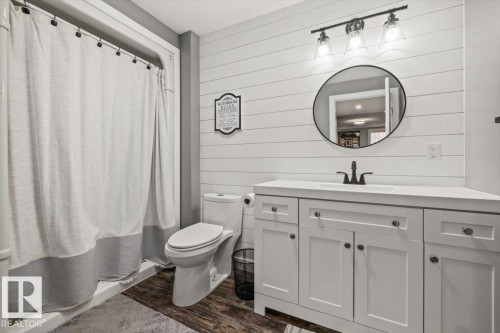 Full vanity with an integrated sink, black faucet, and white shaker-style cabinetry - 40 Hampton Place, Stony Plain, AB 