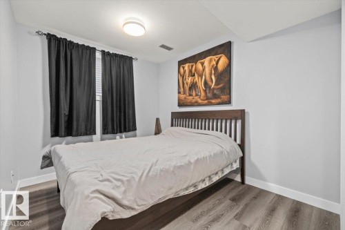 Recessed window with dark panel curtains, ceiling-mounted light fixture, and wood-finish flooring - 40 Hampton Place, Stony Plain, AB 