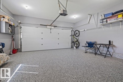 Spacious garage with an epoxy-coated floor, automatic garage door opener, and integrated wall shelving - 40 Hampton Place, Stony Plain, AB 
