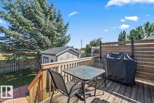 Expansive wood deck with a privacy screen, wood railings, and a storage shed - 40 Hampton Place, Stony Plain, AB 