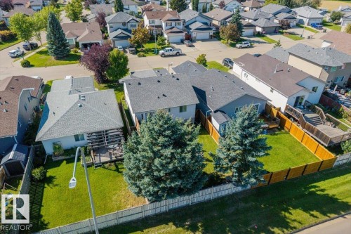 Manicured lawn, mature trees, wood fence, multi-level deck, and established neighborhood setting - 40 Hampton Place, Stony Plain, AB 
