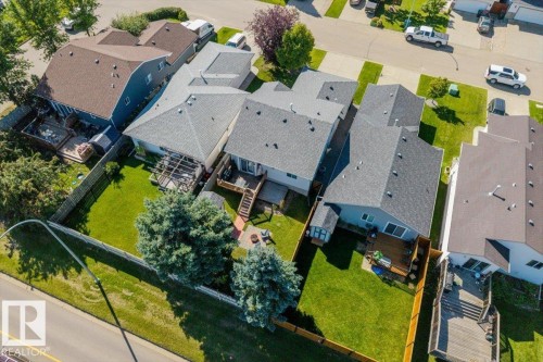 Expansive backyard with manicured lawn, mature trees, and a wooden deck - 40 Hampton Place, Stony Plain, AB 