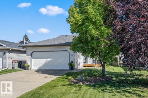 Attached garage with a white panel door, concrete driveway, and a shingle roof - 40 Hampton Place, Stony Plain, AB 