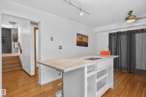 Kitchen island with integrated stainless steel sink, light-toned countertop, and open shelving - 17103 92 Street Nw, Edmonton, AB 