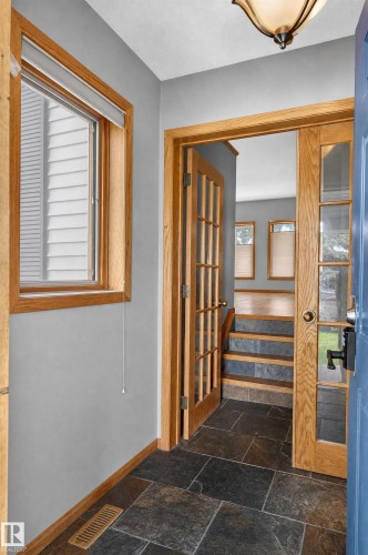 Foyer with slate tile flooring, natural wood-finish trim, and French doors - 17103 92 Street Nw, Edmonton, AB 