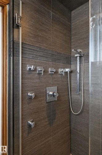 Textured grey wall tiles with a glass mosaic accent band, multiple shower heads, and chrome fixtures - 17103 92 Street Nw, Edmonton, AB 