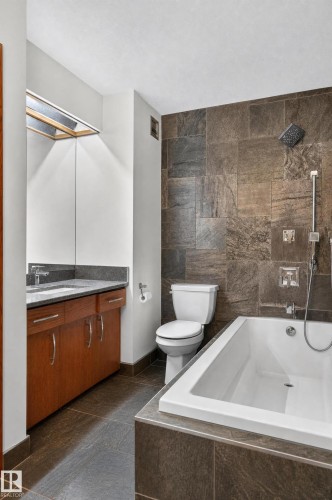 Tiled tub surround with a built-in soaking tub, a tiled shower wall with a rain shower head, a wood-finish vanity with a stone countertop, and a large mirror - 17103 92 Street Nw, Edmonton, AB 