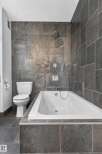 Contemporary bathroom featuring a white soaking tub, tiled tub surround, and a coordinating shower with a rainfall showerhead - 17103 92 Street Nw, Edmonton, AB 