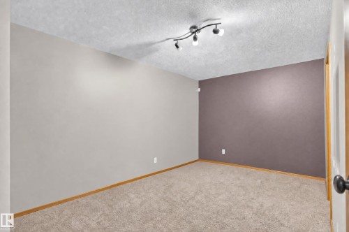 Wall-to-wall carpeting with a neutral color palette, track lighting, and a contrasting accent wall - 17103 92 Street Nw, Edmonton, AB 