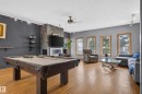 Wood-finish flooring, a stone-accented fireplace, built-in shelving, track lighting, and multiple windows - 17103 92 Street Nw, Edmonton, AB 