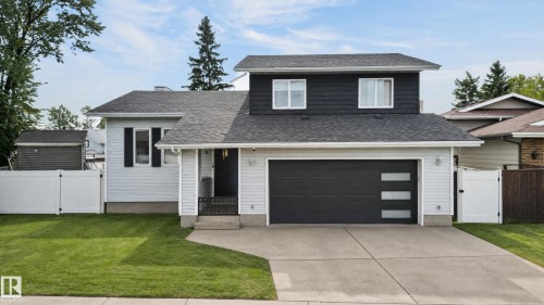 Contemporary exterior featuring light siding, dark horizontal siding, a dark garage door with frosted glass panels, and a concrete driveway - 17103 92 Street Nw, Edmonton, AB 