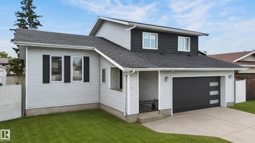 Two-story residence featuring light gray siding, dark gray shake siding accents, and a dark gray garage door with frosted glass panels - 17103 92 Street Nw, Edmonton, AB 