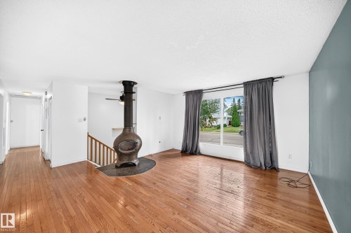 Hardwood-finish flooring, built-in stove, large window, full-height wall, and wooden staircase - 11007 37 Avenue Nw, Edmonton, AB 