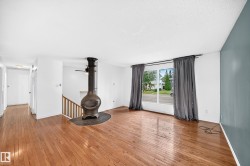 Hardwood-finish flooring, built-in stove, large window, full-height wall, and wooden staircase - 